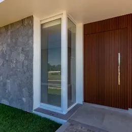 Vista parcial de um ambiente interno com parede de vidro e piso claro.