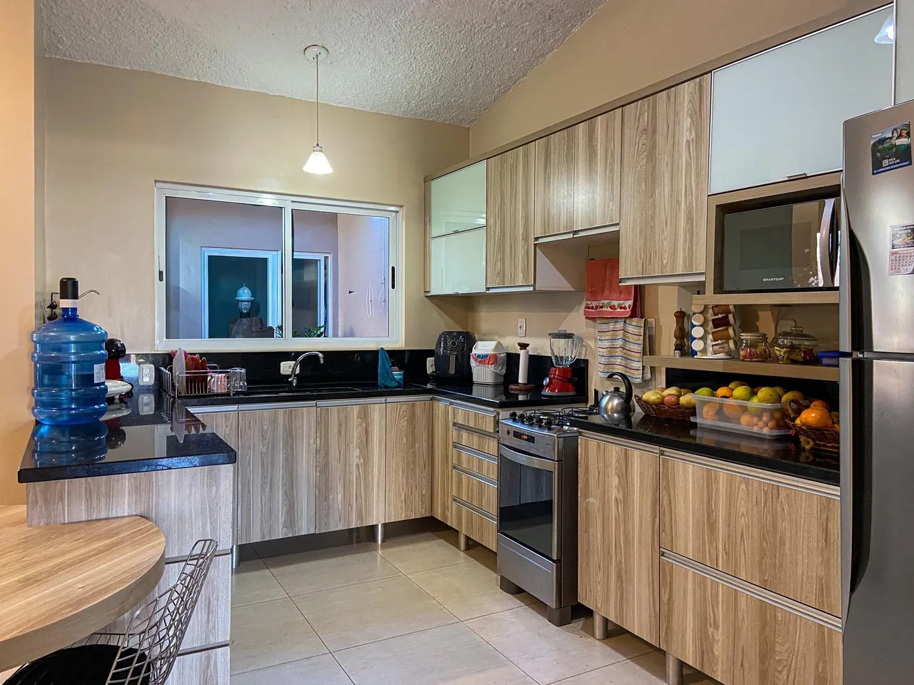 Cozinha moderna com armários de madeira e bancadas escuras.