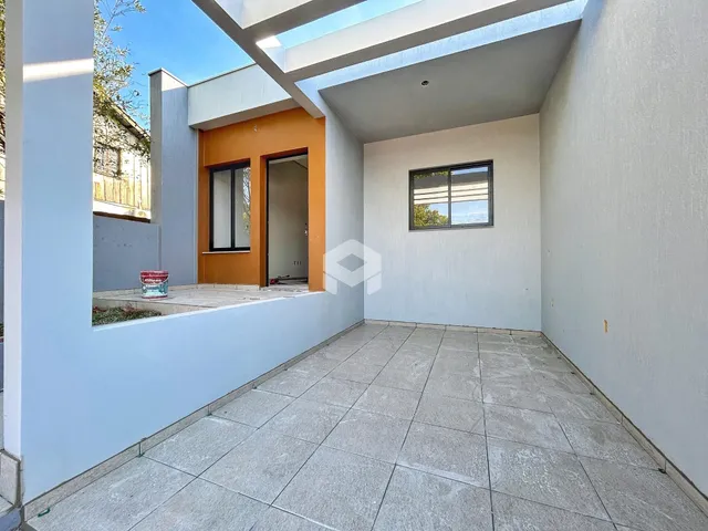 Área externa com piso de cerâmica e parede branca de uma residência.