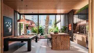Ambiente interno de uma sala de estar com cozinha integrada e vista para o exterior.