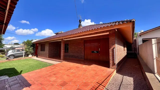 Fachada de uma casa de tijolos vermelhos com telhado de telhas e pátio de cerâmica.