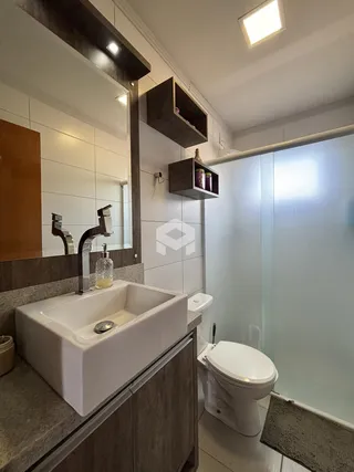 Foto interna de um banheiro moderno com box de vidro e vaso sanitário.