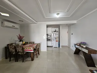 Sala de jantar com mesa de madeira e cadeiras em um imóvel.