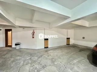 Espaço interno amplo com piso de concreto e estrutura de teto exposta.