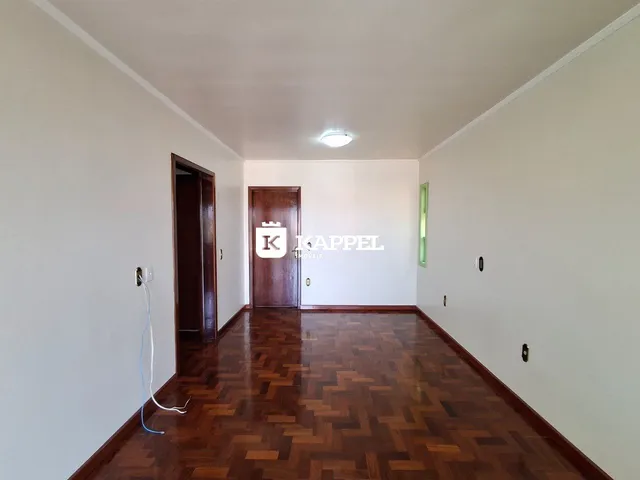 Hall de entrada com piso de madeira escura e paredes brancas.