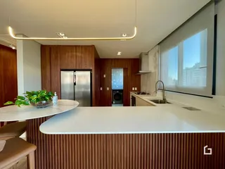 Foto de uma cozinha moderna com armários de madeira e bancada branca.
