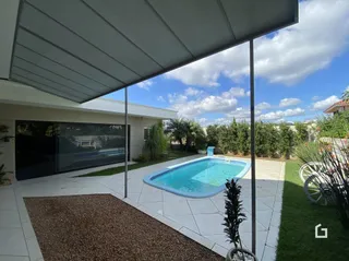 Piscina externa com deck e jardim.