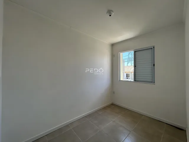 Ambiente interno de uma sala com piso de cerâmica e paredes brancas.