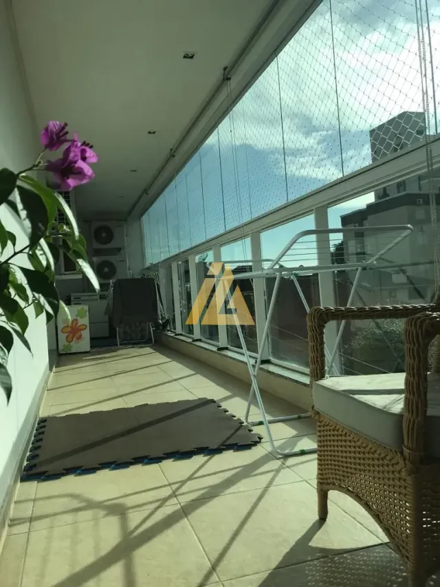 Vista externa de uma varanda com grade metálica e cadeira de vime.