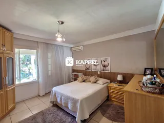 Quarto com cama e janela com cortinas brancas e ar-condicionado.