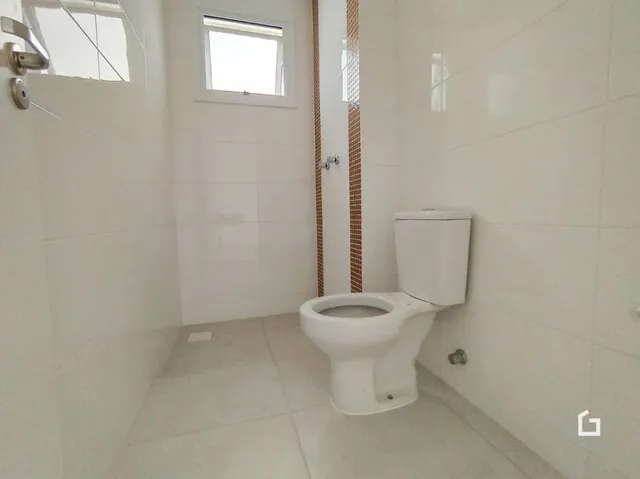 Foto de um banheiro com revestimento branco e vaso sanitário.