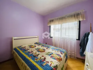 Quarto com cama e janela em ambiente com paredes roxas.
