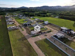Vista aérea de um terreno com áreas verdes e construções dispersas.
