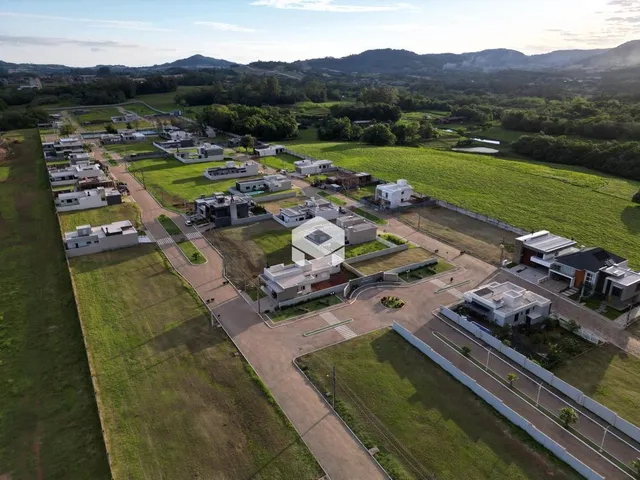 Vista aérea de um terreno com áreas verdes e construções dispersas.