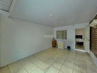 Interior de uma sala com piso de cerâmica clara e paredes brancas.