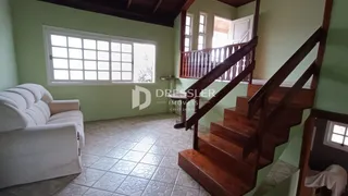 Sala de estar com piso de cerâmica e escadaria de madeira.