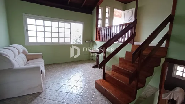 Sala de estar com piso de cerâmica e escadaria de madeira.