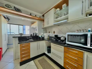 Uma cozinha com armários brancos e bancadas escuras em um imóvel no Brasil.
