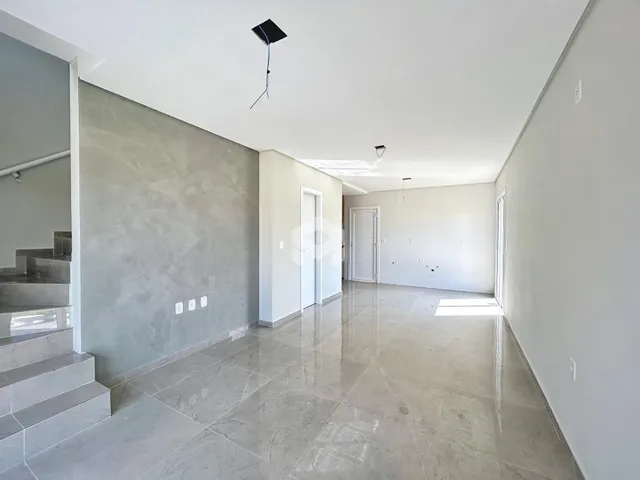 Interior de um espaço amplo com piso de cerâmica clara e paredes brancas.
