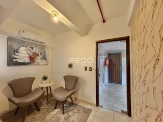 Sala de estar com dois assentos e uma pintura na parede.