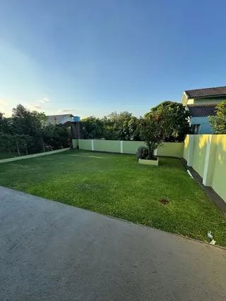 Vista externa mostrando um gramado verde bem cuidado e uma cerca de limite.