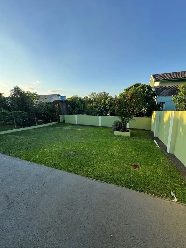 Vista externa mostrando um gramado verde bem cuidado e uma cerca de limite.