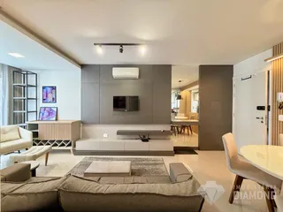 Sala de estar moderna com sofá e painel de TV em um apartamento.