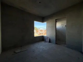Uma sala vazia com paredes brancas e piso de concreto em uma residência.