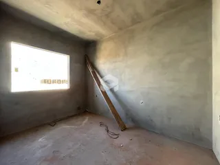 Interior de um cômodo com paredes de concreto aparente e vigamento de madeira.