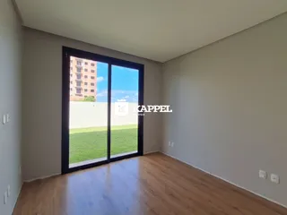 Vista de uma sala com porta de vidro que dá para um gramado verde.