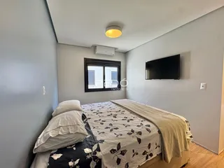 Quarto com cama e televisão montada na parede.