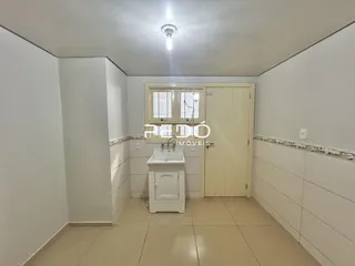 Corredor interno com paredes brancas e piso de cerâmica claro.