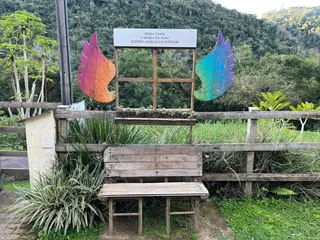 Foto externa de um jardim com cerca de madeira e decorações de penas coloridas.