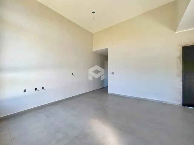 Vista interna de um espaço amplo com paredes brancas e piso de concreto.