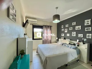Quarto com cama de casal e cabeceira branca em um ambiente bem iluminado.
