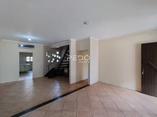 Ambiente interno de uma sala com piso de cerâmica e escadaria visível.