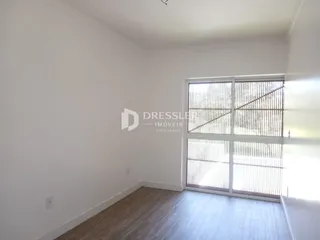 Ambiente interno com piso de madeira e grande janela.