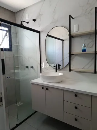 Banheiro moderno com box de vidro e bancada branca.
