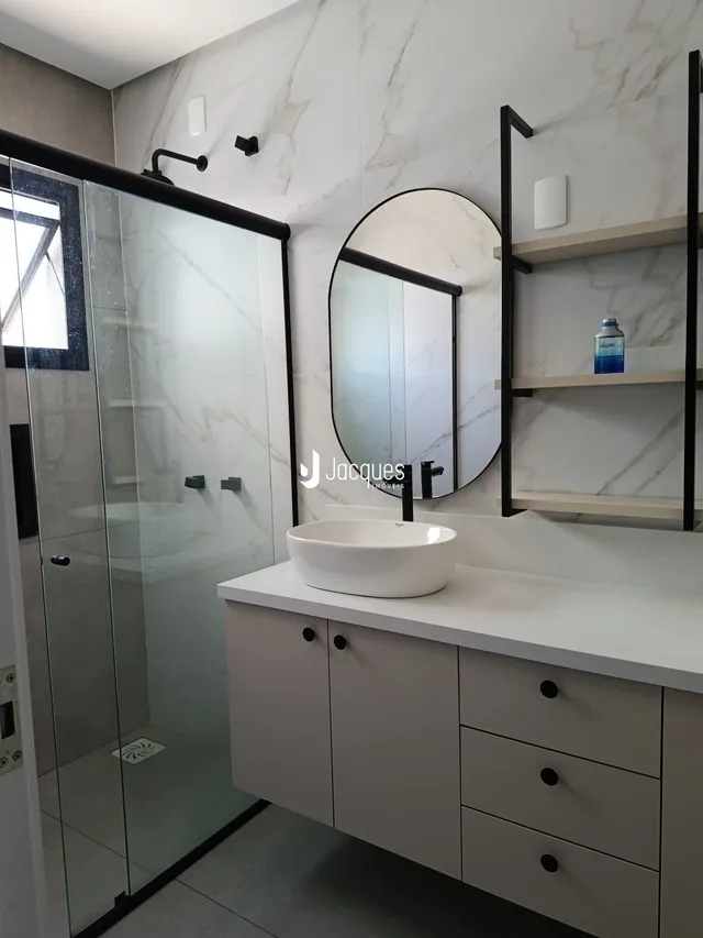 Banheiro moderno com box de vidro e bancada branca.
