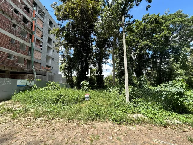 Vista externa de um prédio residencial parcialmente coberto por vegetação densa.