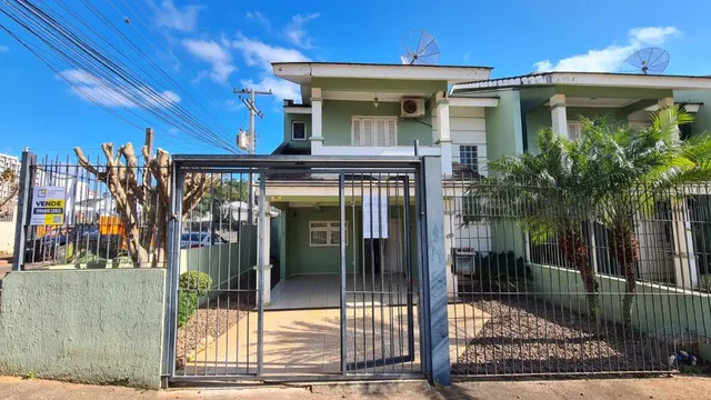 Fachada de uma residência em Lajeado, Brasil, com portão de metal e vegetação.