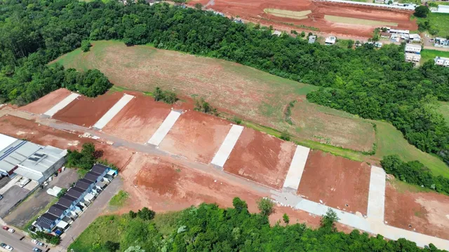 Vista aérea de um terreno com áreas de terra cultivada e vegetação densa ao redor.