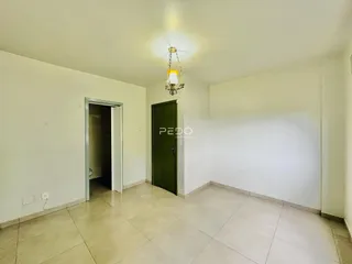 Vista interna de um corredor com paredes brancas e piso de cerâmica.