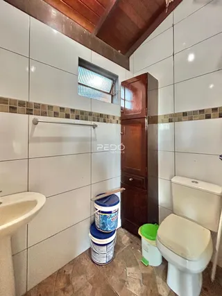 Foto interna de um banheiro com revestimento de cerâmica branca e piso de terracota.