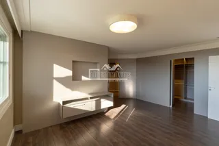Sala de estar com piso de madeira e parede neutra.