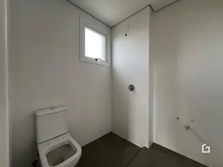Foto de um banheiro interno com azulejos escuros e paredes brancas.
