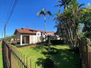Foto da fachada de uma casa em Lajeado, Brasil, com um jardim verde e cerca de madeira.