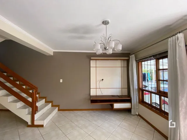 Um corredor com escada de madeira e piso de cerâmica.