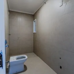 Interior de um banheiro com paredes claras e um vaso sanitário branco.