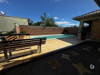Vista externa de uma piscina e área de lazer com muro de tijolos.